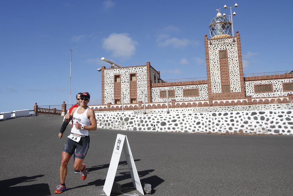 Triathlete running beside Faro de la Entallada